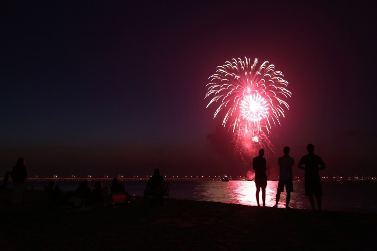 People gather along the beach near the Aeries on the Bay area of Virginia Beach to watch holiday fireworks at dusk on Saturday, July 12, 2014. The fireworks are privately- funded by the three area civic leagues along that part of the bay, including Chic's Beach. (Martin Smith-Rodden | The Virginian-Pilot)