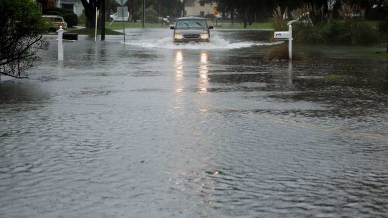 A vehicle makes it way slowly through the rising water on Lynnhaven Drive in Virginia Beach on Friday, Oct. 2, 2015, several hours before high tide. (Vicki Cronis-Nohe | The Virginian-Pilot)